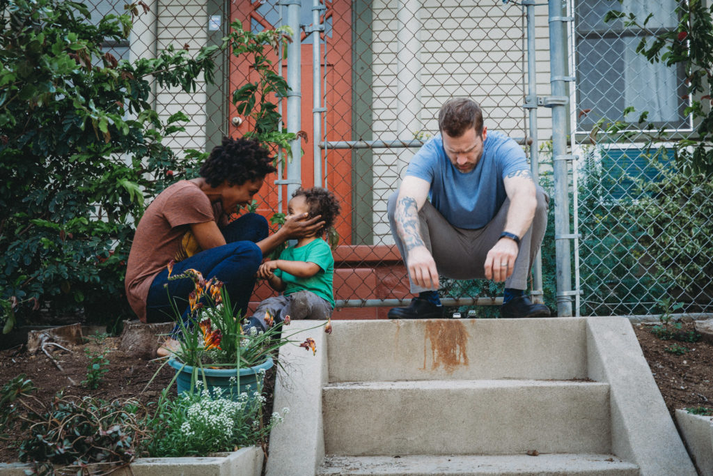 Mom holding toddlers head and hanging outside with dad