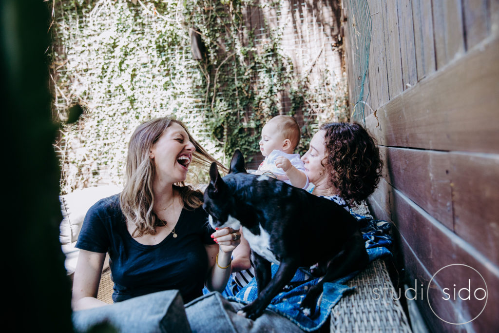 Baby pulls mama's hair while young family sits outside in Silver Lake, Los Angeles, CA 