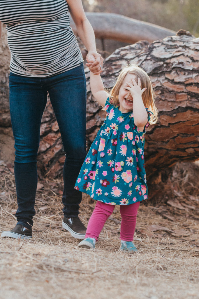 Little girl laughs and covers her face while holding mom's hand in Griffith Park photo session