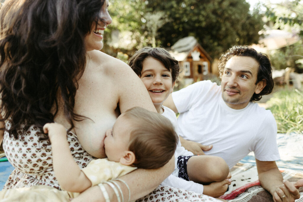 Mother nurses her baby while sitting with her family